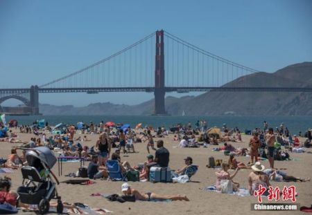 　　当地时间5月25日，美国旧金山市民在金门大桥附近的海滩纳凉。 中新社记者 刘关关 摄