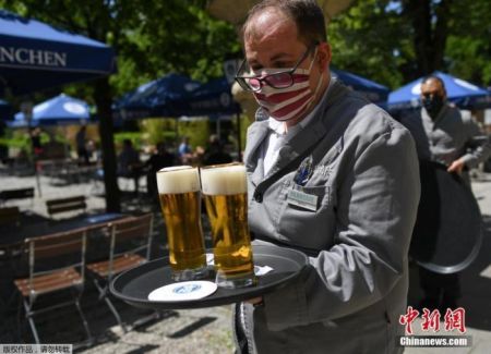 　　资料图：德国慕尼黑一家啤酒店重新开业后，服务员佩戴口罩上岗。