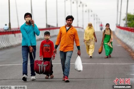 　　当地时间3月27日，一名印度工人和家人走在高速公路上，返回家乡。