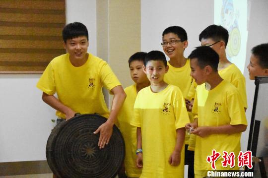 图为华裔青少年当日在广西自治区博物馆人员的指导下，体验铜鼓传音。　钟建珊　摄