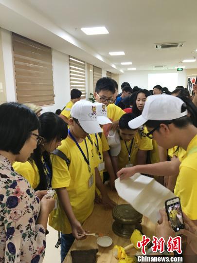 图为华裔青少年当日在广西自治区博物馆人员的指导下尝试拓印一面小的铜鼓。　钟建珊